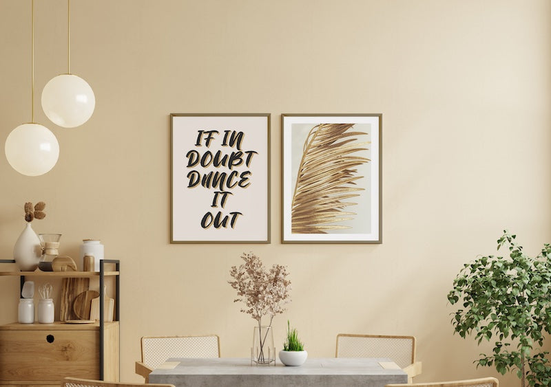 Gold leaf botanical wall art styled with a graphic inspirational quote print pictured in a neutral dining room.