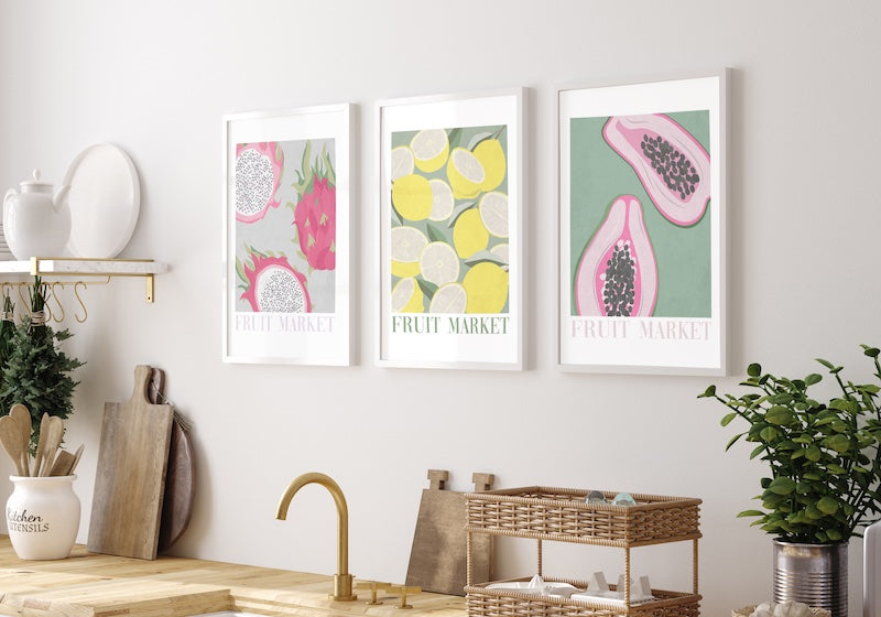 Graphic wall art set of 3 fruit pictured in a neutral and white kitchen.